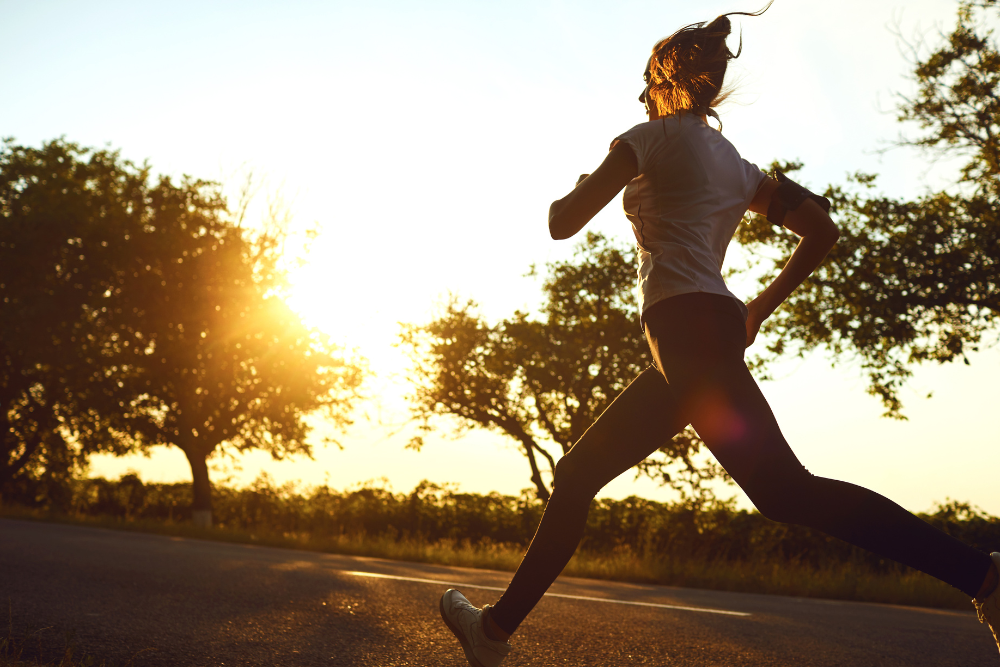Nainen juoksee auringonlaskussa – kuva symboloi voimaa, toipumista ja luonnollista hyvinvointia rintaoperaation jälkeen.