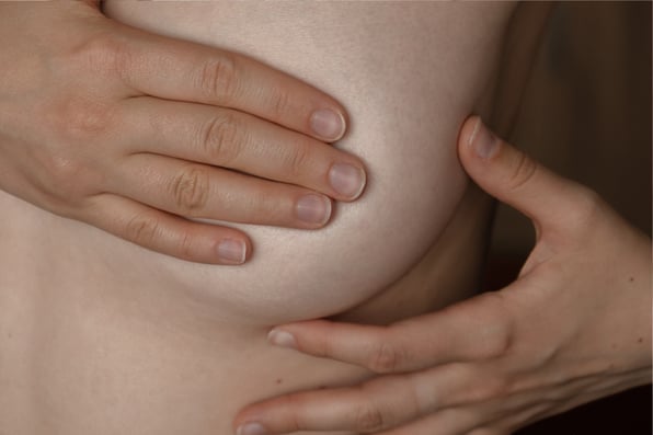 Nainen tutkii rintaansa omatarkkailun yhteydessä – säännöllinen rintojen tutkiminen auttaa havaitsemaan muutokset ajoissa ja tukee terveyttä.